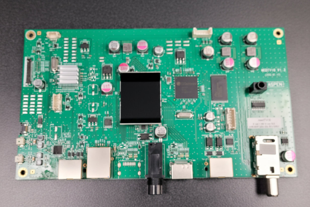 Green electronic circuit board with various components on a gray background